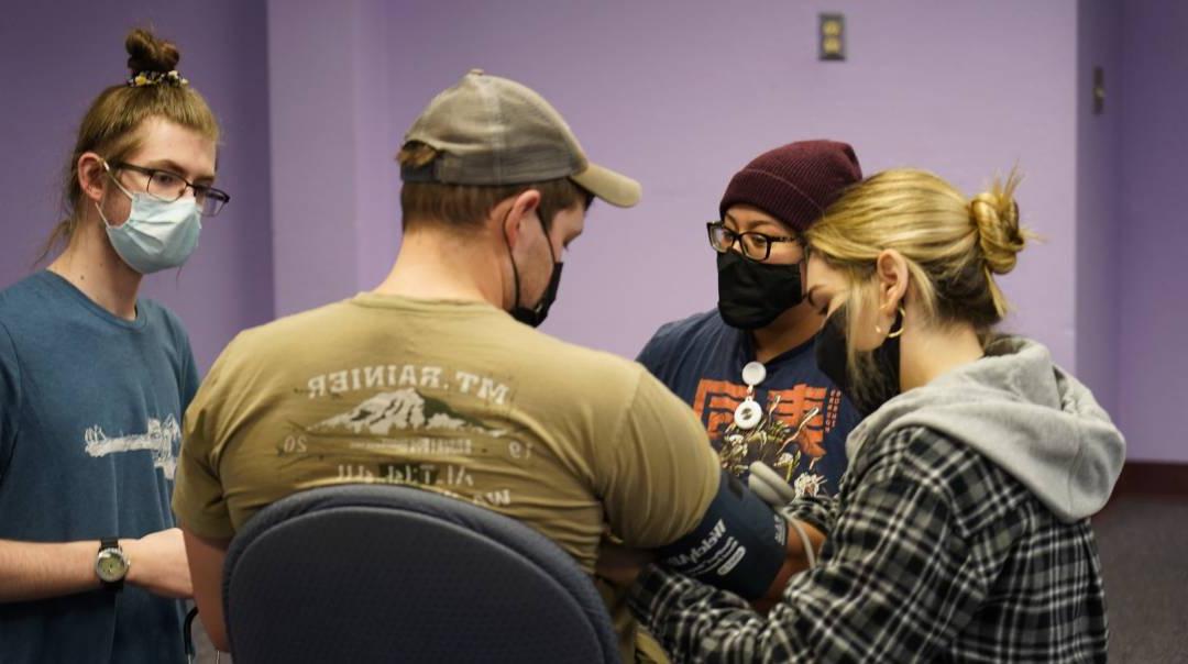 A cluster of EMT students are running tests on one of their peers