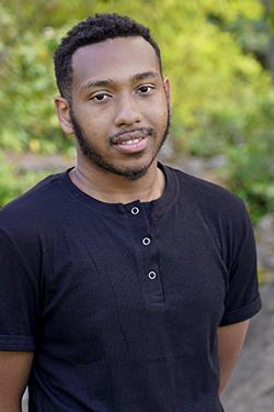 Image of a man with short hair wearing a black shirt. 